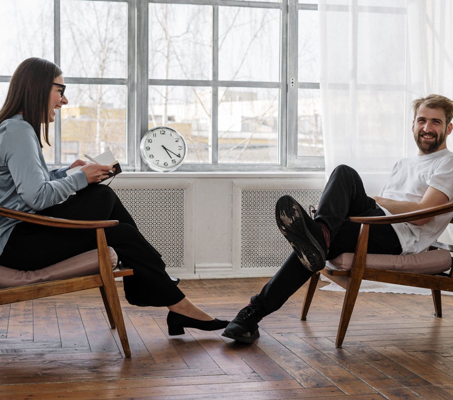 2 Women Sitting on Brown Wooden Chair